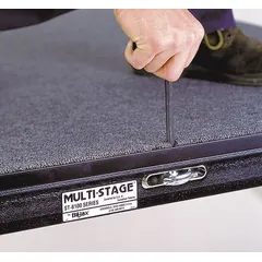 Wood-framed carpeted stage platform. Overall dimensions 40 ft length by 24 ft width. Includes 77 legs for support. Suitable for temporary or permanent staging in event, performance, and presentation settings.