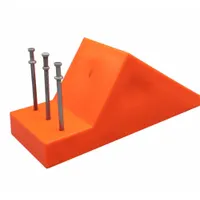 Orange plastic pipe chock used to secure pipes and cylindrical loads during transport or storage, preventing rolling. Overall length 8 in, width 3 in, height 3-1/2 in. Suitable for material handling and industrial applications