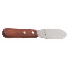 This spreader features a serrated stainless steel blade and a brown wood handle, with an overall length of 8 1/4 in. It is used for applying and smoothing materials such as adhesives, sealants, or food products in industrial kitchens, food processing, or general maintenance tasks.