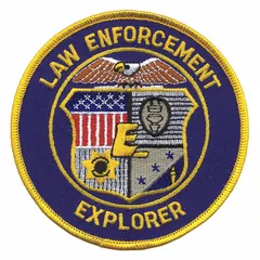 This embroidered insignia is a 4-inch blue plastic patch designed for sew-on attachment to uniform shoulders. It is used for identification purposes in law enforcement explorer programs and similar youth or volunteer public safety organizations.