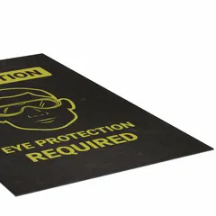 This safety entrance mat is made of polypropylene with an adhesive backing, measuring 3 ft x 5 ft and 1/8 in thick. It is designed for floor placement at entry points to indicate that eye protection is required, helping reinforce workplace safety protocols in areas where eye hazards exist.
