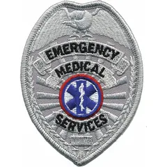 This embroidered badge measures 2 1/2 inches by 3 1/2 inches and features a gold design on a plastic base. It is attached by sewing onto uniforms, caps, or bags for identification purposes.