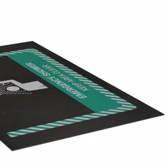 This entrance mat is designed for placement in front of emergency shower stations to absorb water and provide slip resistance. It is made of polypropylene with an adhesive backing for secure floor placement. The mat measures 3 ft x 5 ft with a 1/8 in thickness and is black in color.