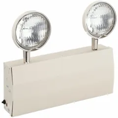 Indoor surface-mount emergency light with steel housing in beige. Operates on 120/277V AC, providing 12 W lamp watt and 32 W emergency watt. Features adjustable halogen lamp heads and remote capability. Complies with NFPA 101-1988 standards for egress lighting.